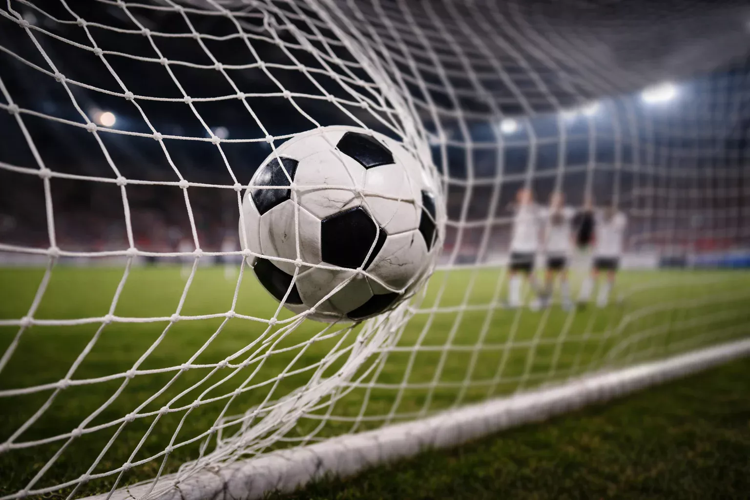 Balón de fútbol entrando en la red de una portería durante un partido nocturno de Europa League